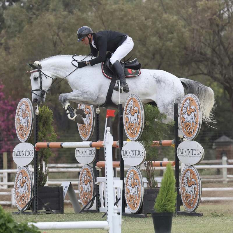 Emile Egen showjumping a grey over a Tack n Togs fence